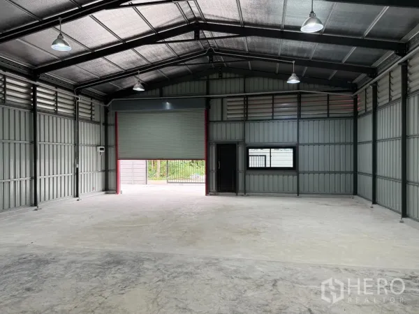 Warehouse for rent in Lat Phrao, Bangkok - Open-plan warehouse floor facing the main roller door with ample lighting and concrete slab.