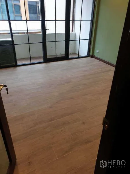 Home Office for rent in Khlong Toei, Bangkok - Compact room with light wood flooring and sliding doors to a small balcony.