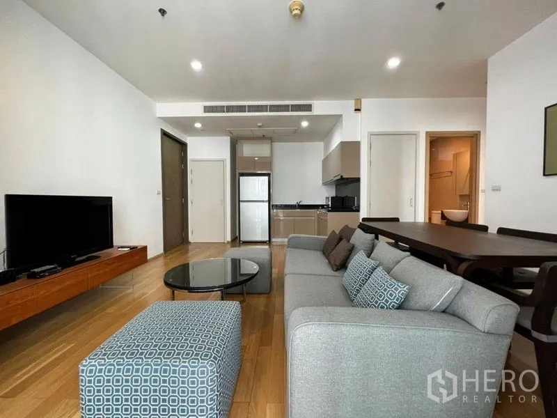 Condominium for rent in Khlong Toei, Bangkok - Wide view of open living area connecting to kitchen and dining, with sofa, coffee table and TV unit.