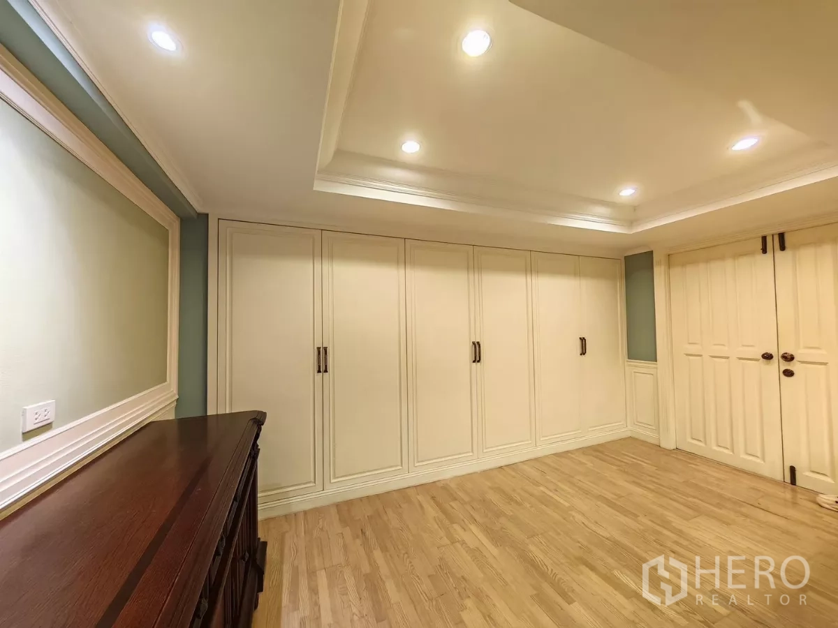 Condominium for rent in Pathum Wan, Bangkok - Room with wall-to-wall wardrobes and wood floors offering generous storage.