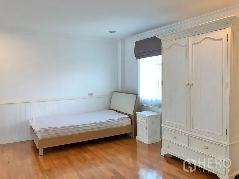 Detached House for rent in Mueang Samut Prakan, Samut Prakan - Guest bedroom with wooden floor, simple bed, white armoire and ample natural light.