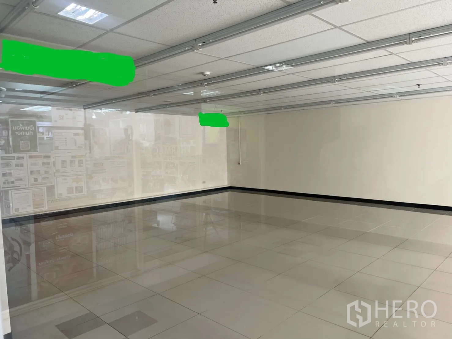 Retail Space for rent in Watthana, Bangkok - Empty retail interior with glossy tiled floors, white walls, and a dropped ceiling with lighting tracks.