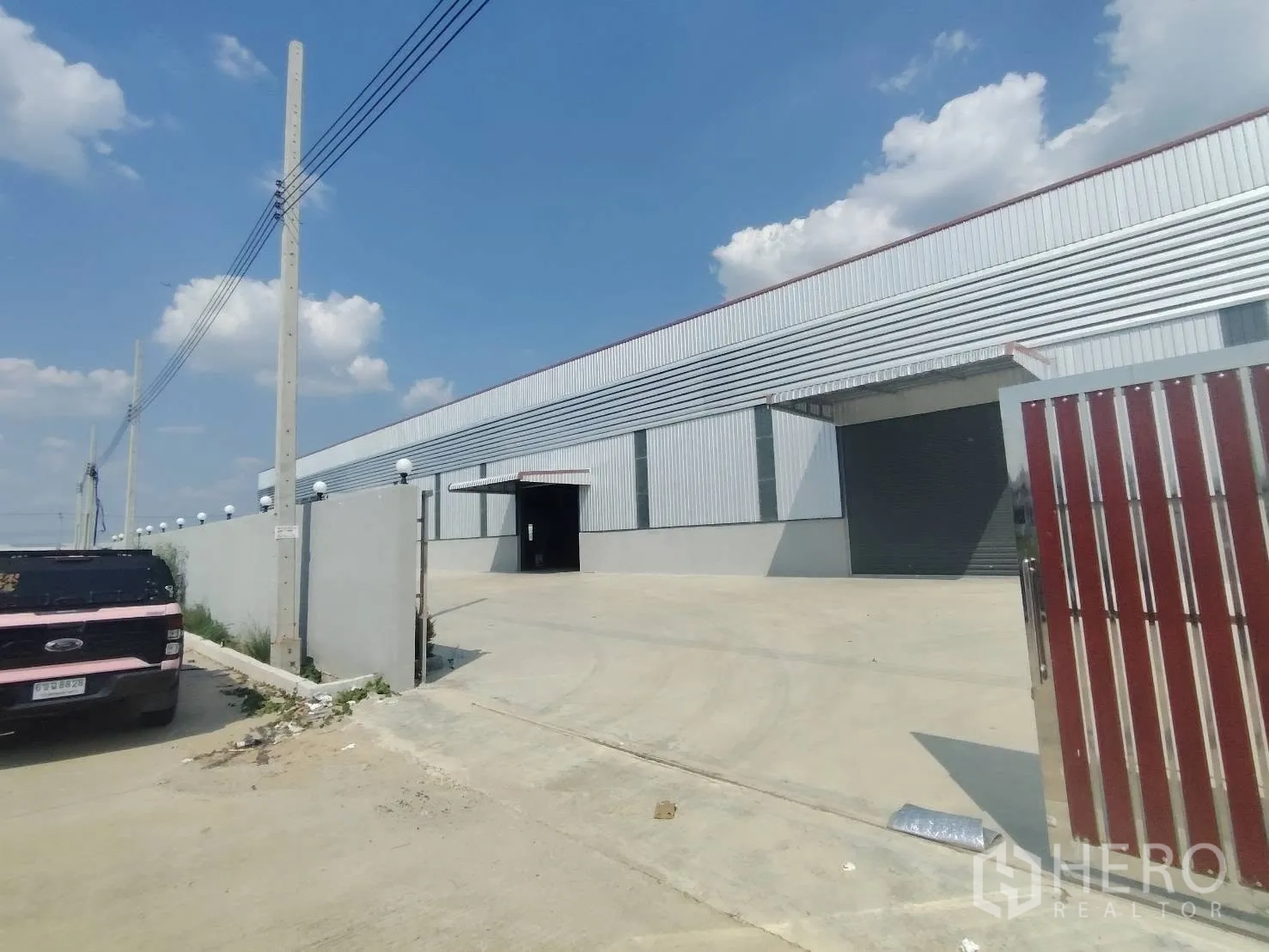 仓库 for rent in Bang Phli, Samut Prakan - 通往仓库的车道与大门，可见卷闸门与围墙。