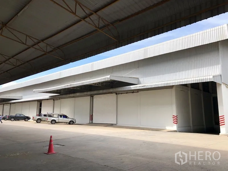 Warehouse for rent in Phra Nakhon Si Ayutthaya - Covered exterior loading area with canopies and on-site parking in front of the warehouse.