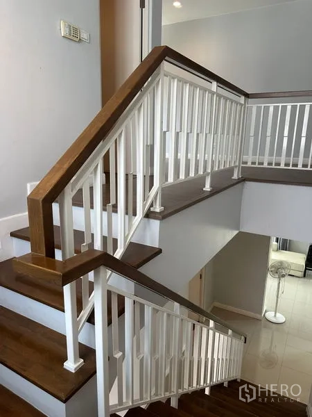 Detached House for rent in Lam Luk Ka, Pathum Thani - Interior staircase with wooden treads and white balustrade.