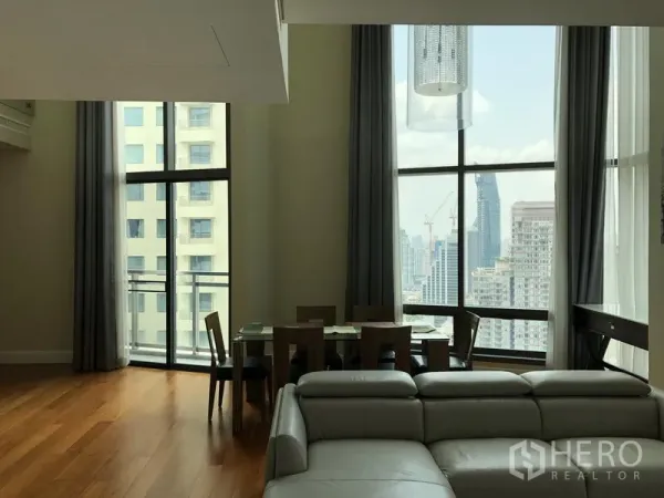 Condominium for rent or sale in Khlong Toei, Bangkok - Dining area by floor-to-ceiling windows and balcony with Bangkok skyline views.