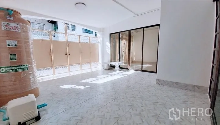 Townhouse for sale - Bright ground-floor area with tiled floor, sliding glass doors and a water tank in a Bang Chak townhouse.