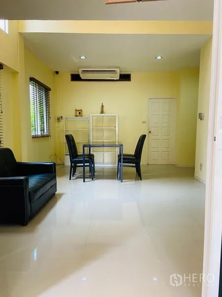 Detached House for rent in Watthana, Bangkok - Bright living area with sofa, small dining set, glossy floors and built-in air conditioner.