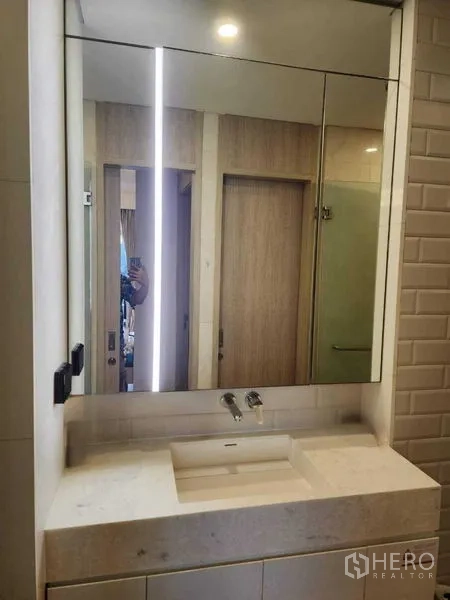 Condominium for rent in Khlong Toei, Bangkok - Sleek bathroom vanity with mirrored cabinets and under-mount sink.