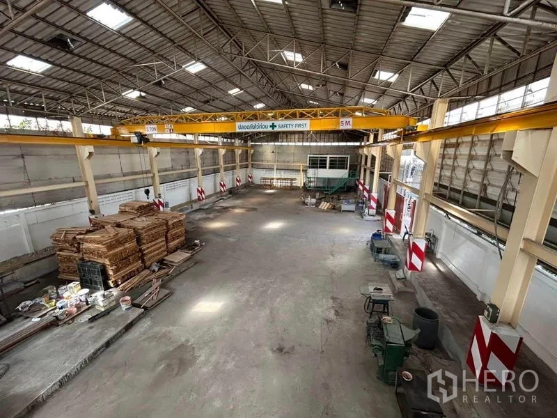 Warehouse for rent in Mueang Samut Prakan, Samut Prakan - Wide shot of the warehouse showing an overhead crane and stacked timber.