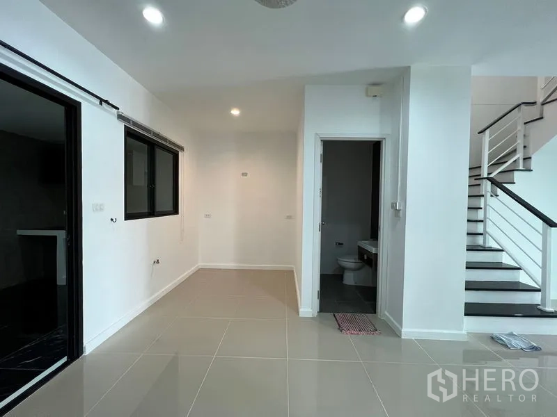 Townhouse for sale in Bang Kapi, Bangkok - Dining area beside guest bathroom and staircase, bright white interior.