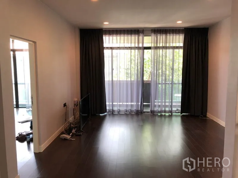 Detached House for rent or sale in Bang Kapi, Bangkok - Family room opening to a balcony through full-height glass with sheer drapes.