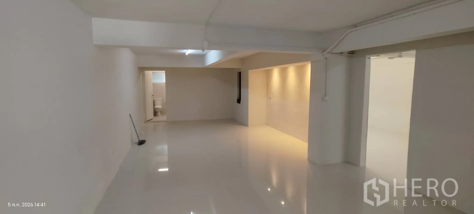 Shophouse for rent in Watthana, Bangkok - Open-plan level with glossy floor and a toilet room at the rear.