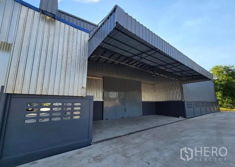 Warehouse for rent in Sai Noi, Nonthaburi - Close-up of warehouse entrance showing large sliding steel doors and a deep canopy for loading operations.