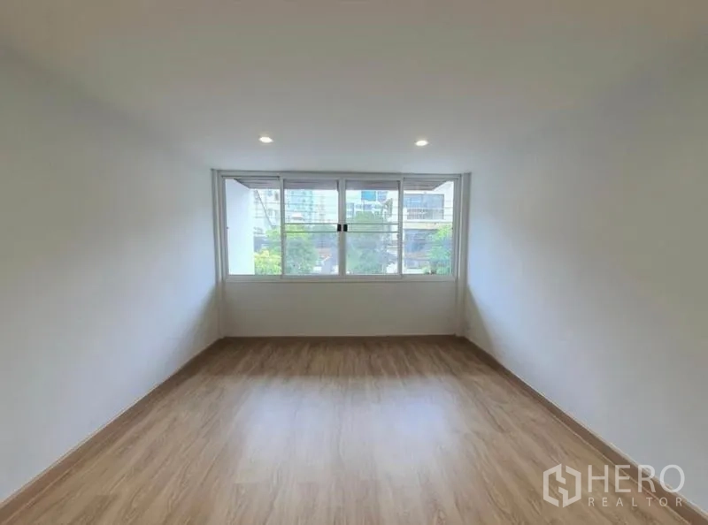 Townhouse for rent in Phaya Thai, Bangkok - Room with wide picture windows overlooking neighborhood greenery and wood flooring.