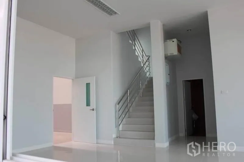 Factory for rent or sale in Lam Luk Ka, Pathum Thani - Bright ground-floor office lobby with white tiles and a staircase with stainless handrail.