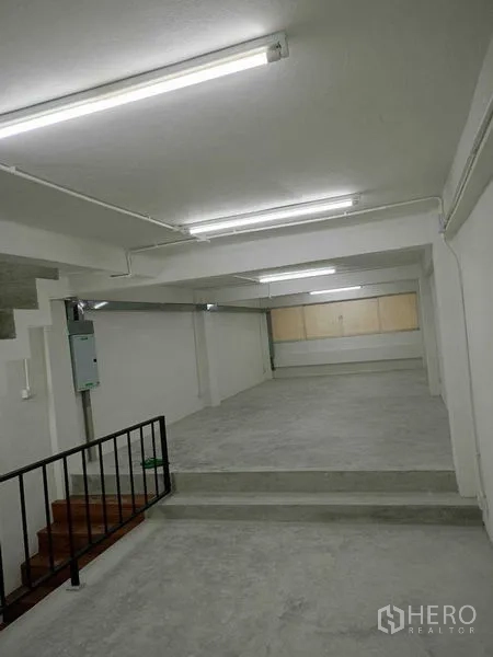 店屋 出租在Watthana, Bangkok - 纵深视角的开放空间，带台阶抬高区与天花灯管。