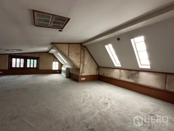 Townhouse for rent in Khlong Toei, Bangkok - Top-floor loft with sloped ceiling, skylights and an expansive carpeted space.