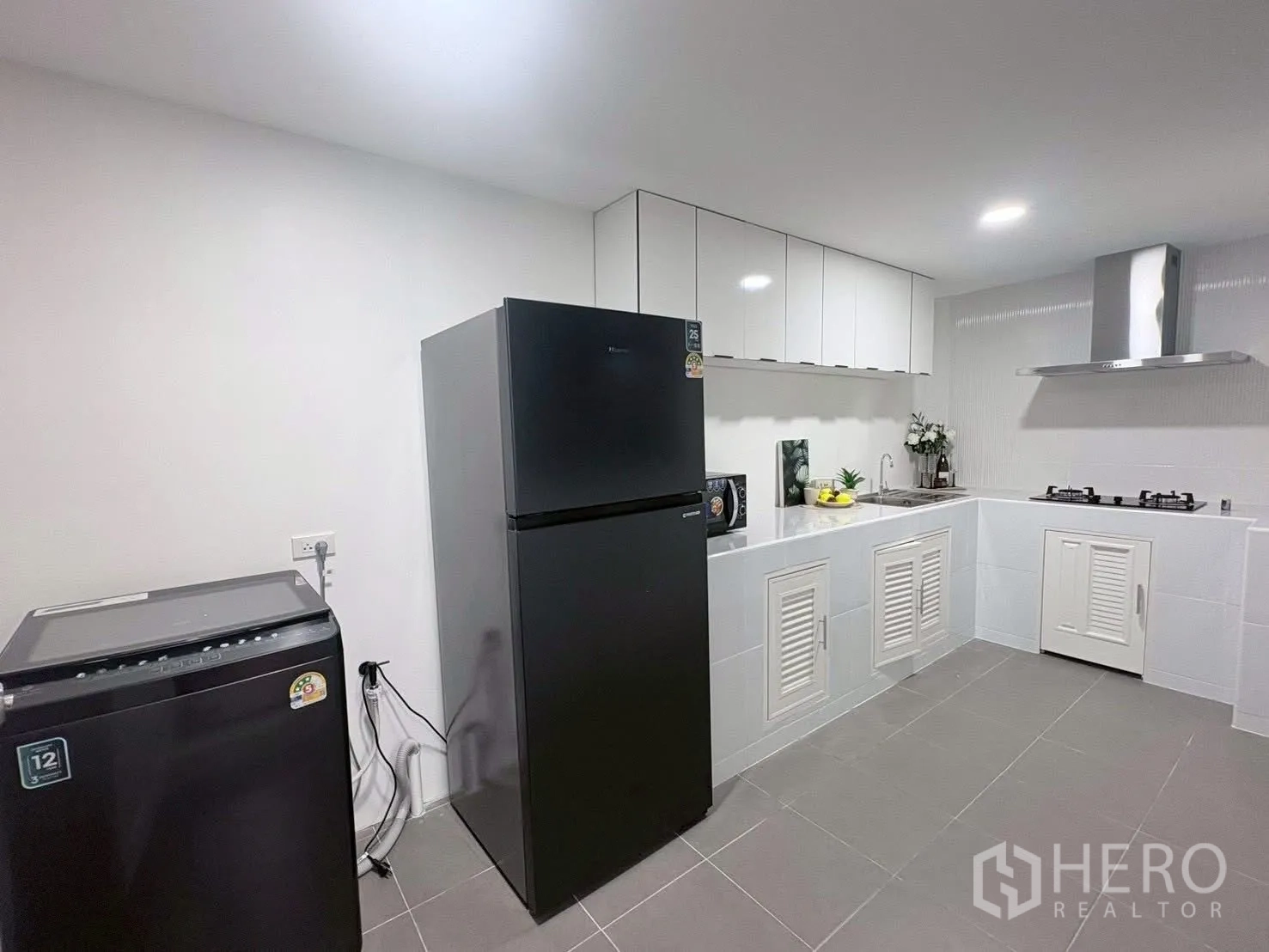 Townhouse for rent in Huai Khwang, Bangkok - Kitchen view with refrigerator and washing machine beside built-in counters.
