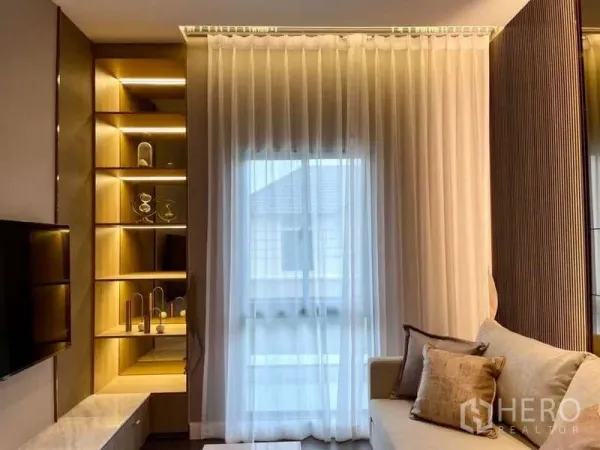 Detached House for rent in Bang Phli, Samut Prakan - Cozy living area with sheer curtains, illuminated built‑in shelves and a soft sofa.