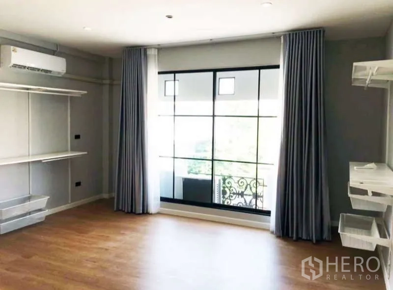 Townhouse for rent or sale in Prawet, Bangkok - Corner bedroom with air conditioner, balcony view, and open wardrobe system.