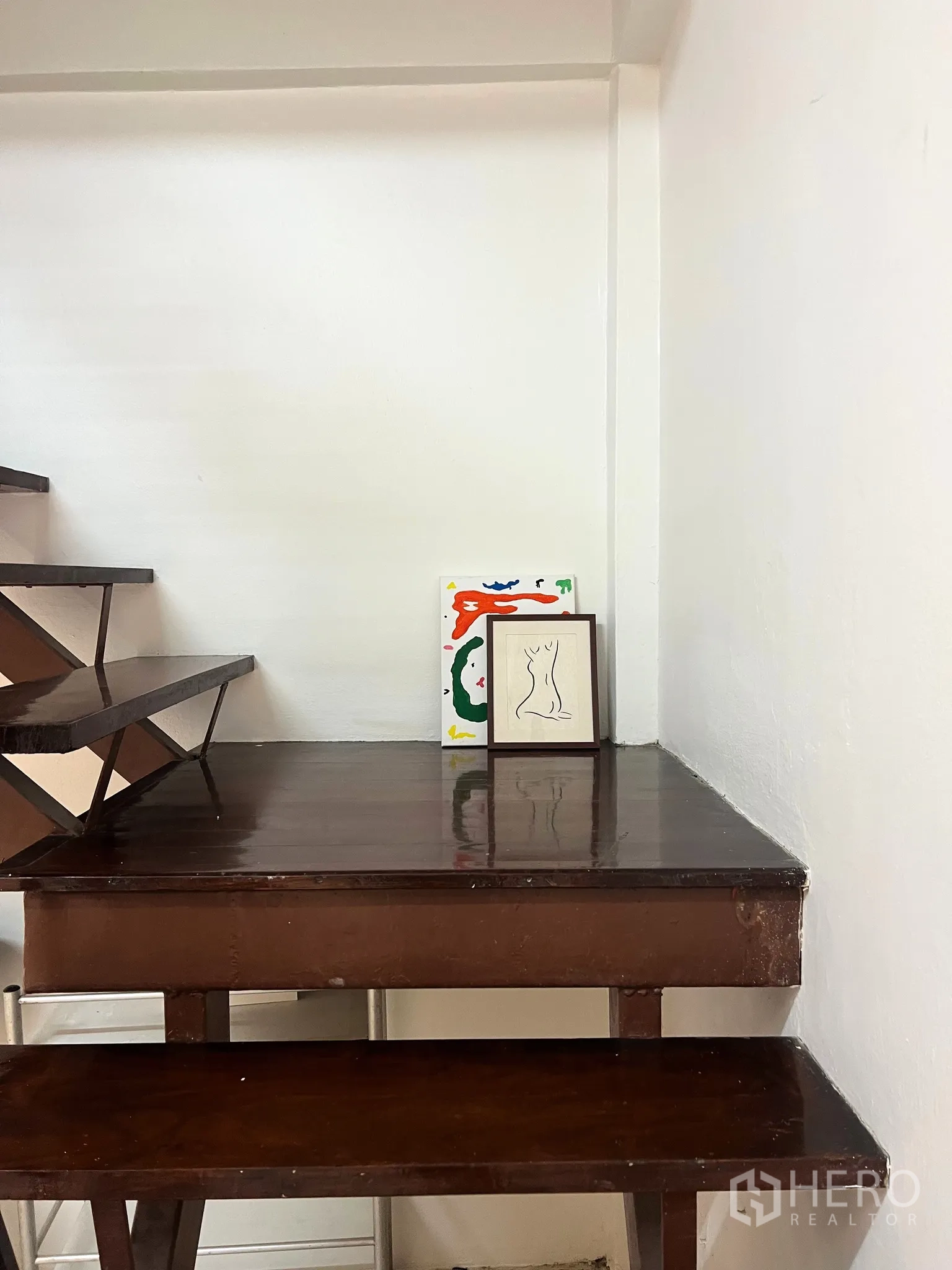 Townhouse for rent - Wooden staircase and landing with dark steps and decorative art frames.