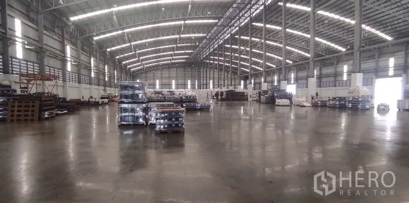 Warehouse for rent in Nong Chok, Bangkok - Expansive high-bay warehouse interior with steel truss roof, polished concrete floor and pallet stacks.
