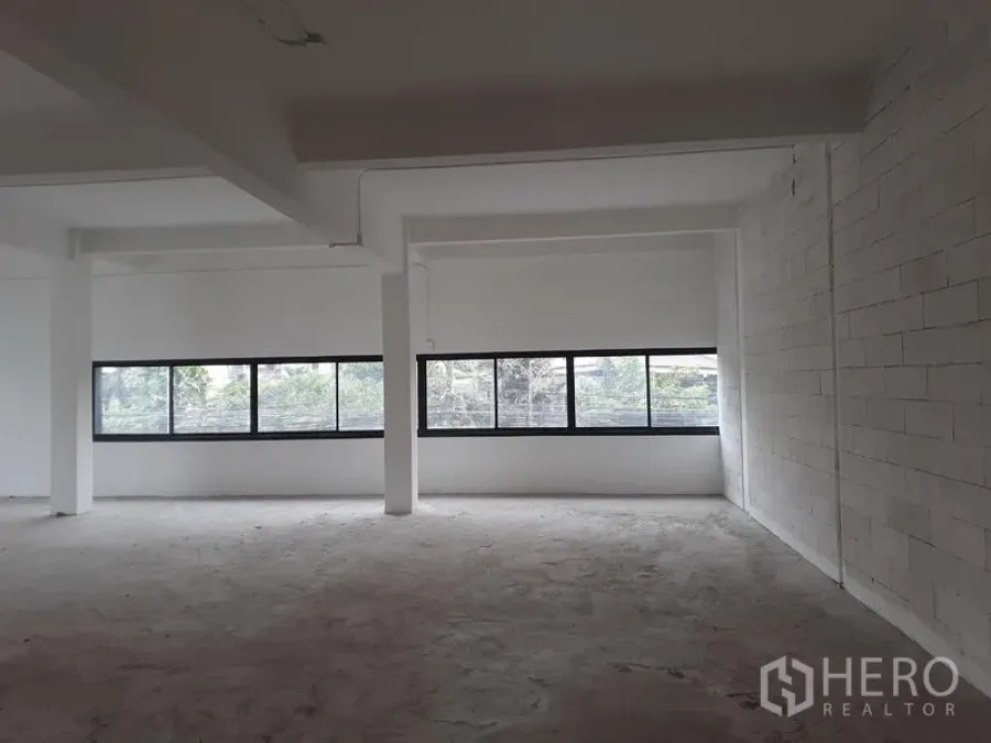 Office Space for rent in Khlong Toei, Bangkok - Open-plan office interior with long horizontal windows, white brick wall and exposed beams in Phra Khanong.