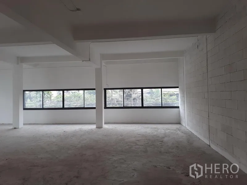 Office Space for rent in Khlong Toei, Bangkok - Open-plan office interior with long horizontal windows, white brick wall and exposed beams in Phra Khanong.