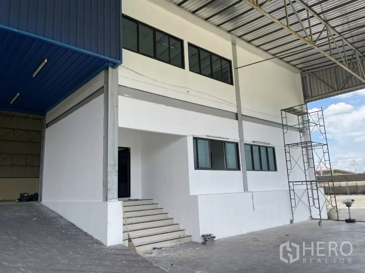 Warehouse for rent in Lat Krabang, Bangkok - Two-storey office block at the warehouse entry with stairs under a metal roof.