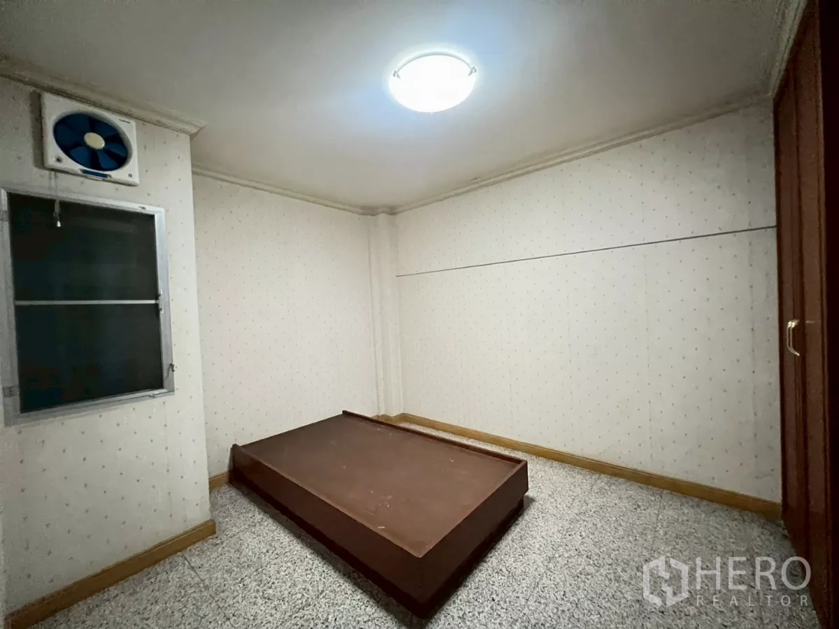 Shophouse for rent in Bang Rak, Bangkok - Simple bedroom or storage room with window fan and terrazzo floor.