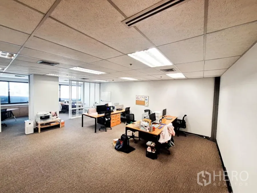 Office Space for rent in Bang Na, Bangkok - Spacious open‑plan workspace with carpet flooring, desks and glass‑partitioned rooms at the far end.