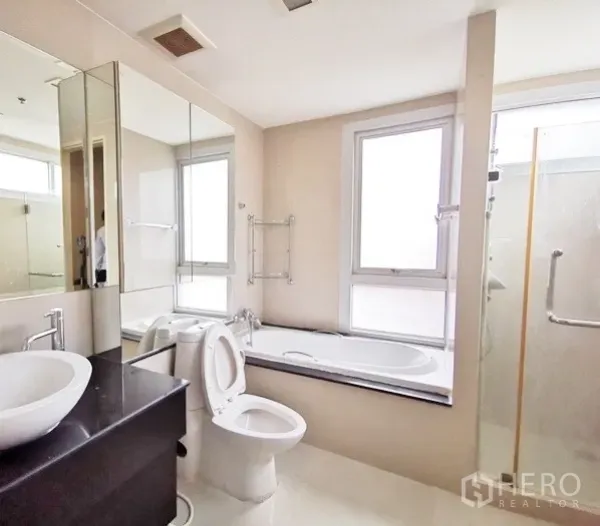 Condominium for rent in Khlong Toei, Bangkok - Master bathroom featuring a soaking tub by the window, separate glass shower and vanity.