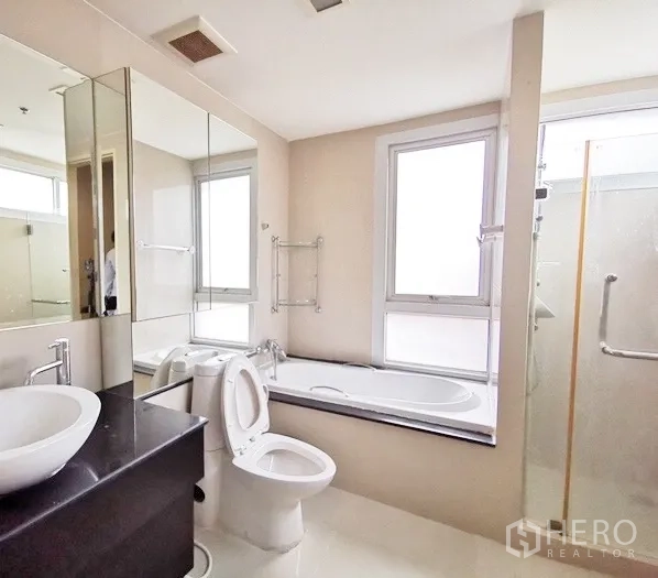 Condominium for rent in Khlong Toei, Bangkok - Master bathroom featuring a soaking tub by the window, separate glass shower and vanity.