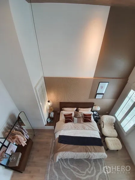 Detached House for rent in Prawet, Bangkok - Overhead view of master bedroom with high ceiling, accent wall and armchair.