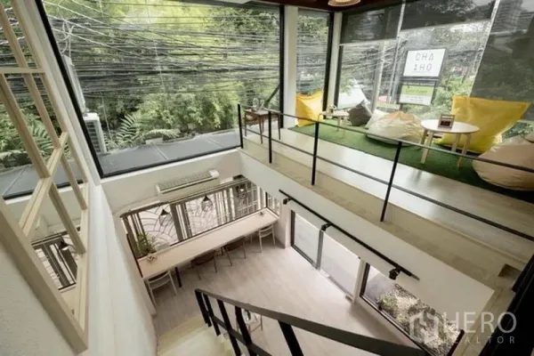 Shophouse for rent in Bang Rak, Bangkok - Loft-style shophouse interior with mezzanine lounge, floor-to-ceiling windows and greenery views near BTS Chong Nonsi.