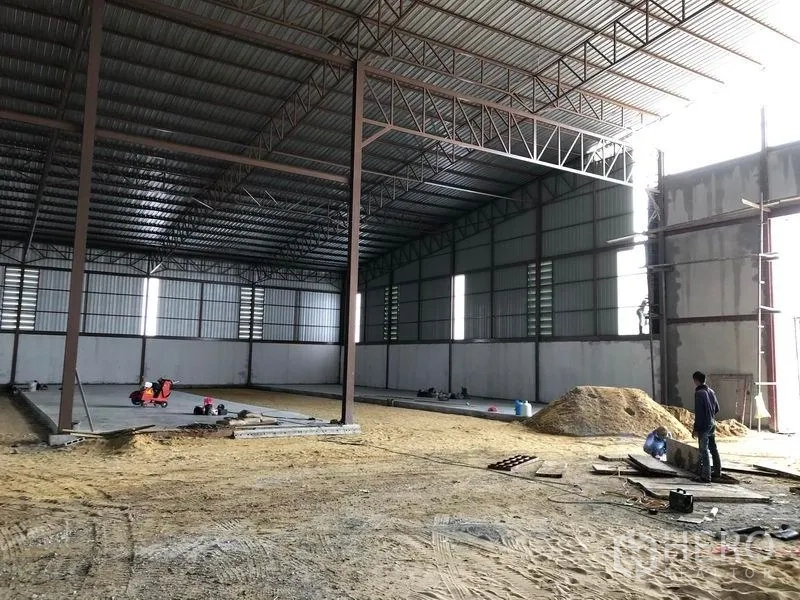 Warehouse for rent or sale in Sai Noi, Nonthaburi - Angled view of the warehouse interior near the entrance with tall walls and ample natural light.