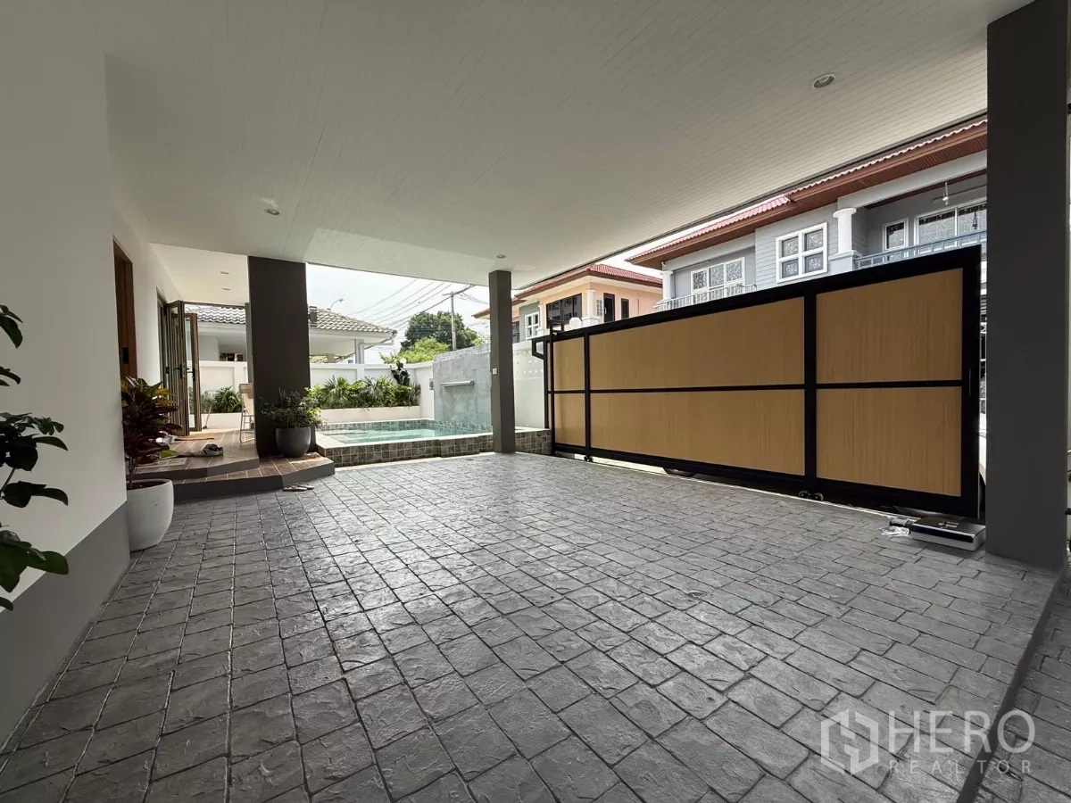 Detached House for sale in Suan Luang, Bangkok - Covered carport with textured paving adjacent to the pool and front gate.