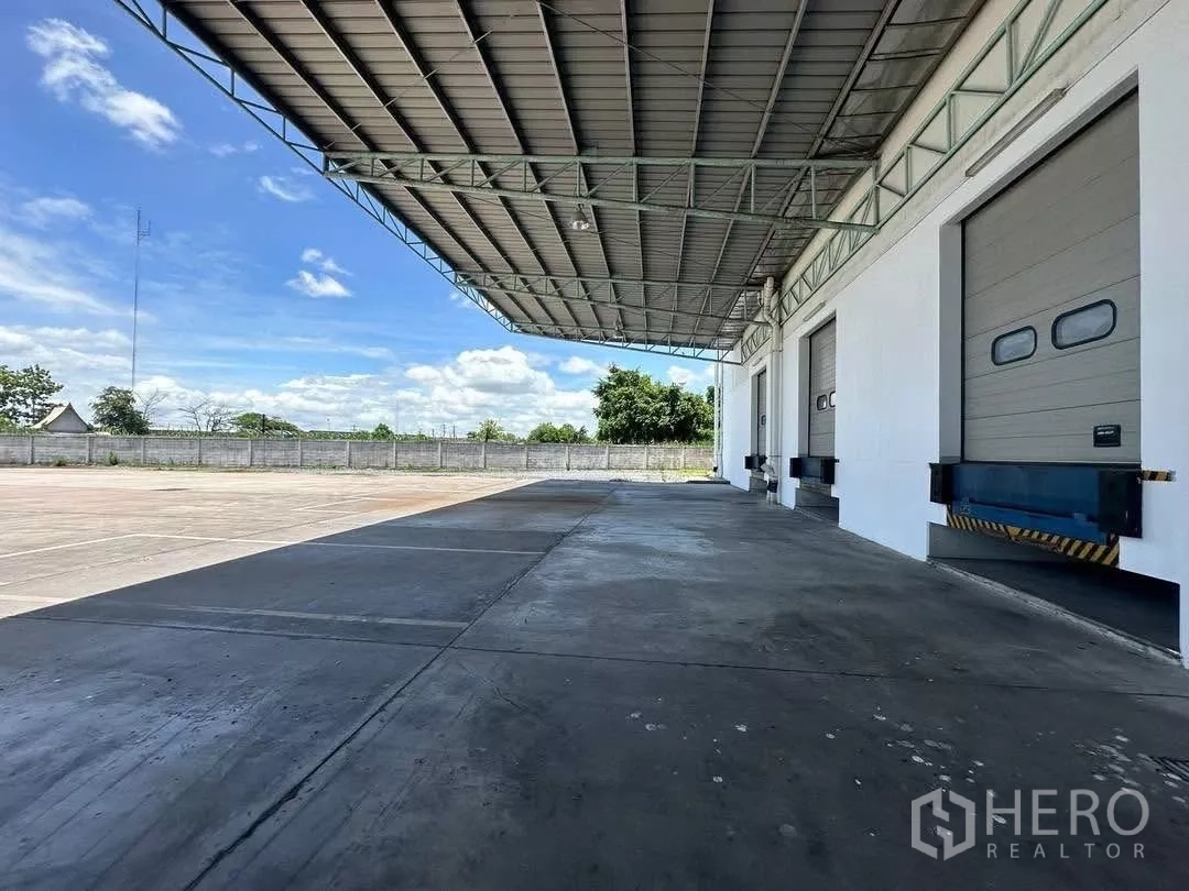 Factory for rent in Si Racha, Chon Buri - Wide apron beneath a metal canopy for trailer maneuvering beside loading docks.