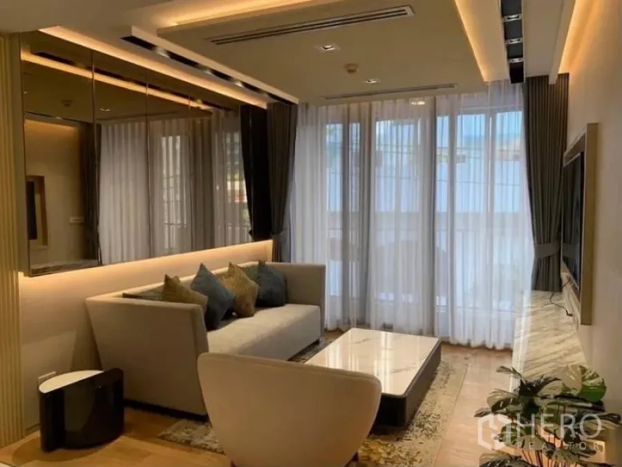 Condominium for rent in Watthana, Bangkok - Modern living room with sofa, marble TV console, floor-to-ceiling sheer curtains and warm recessed lighting.