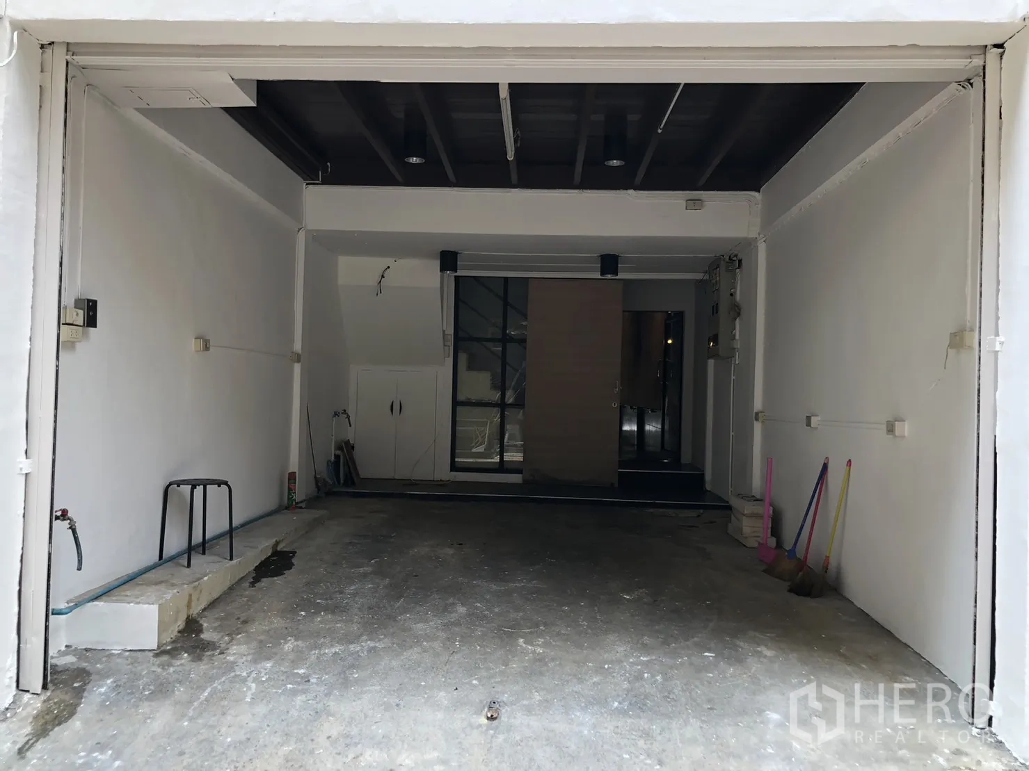 Shophouse for rent - Ground-level garage-style entrance with rolling door and concrete floor.