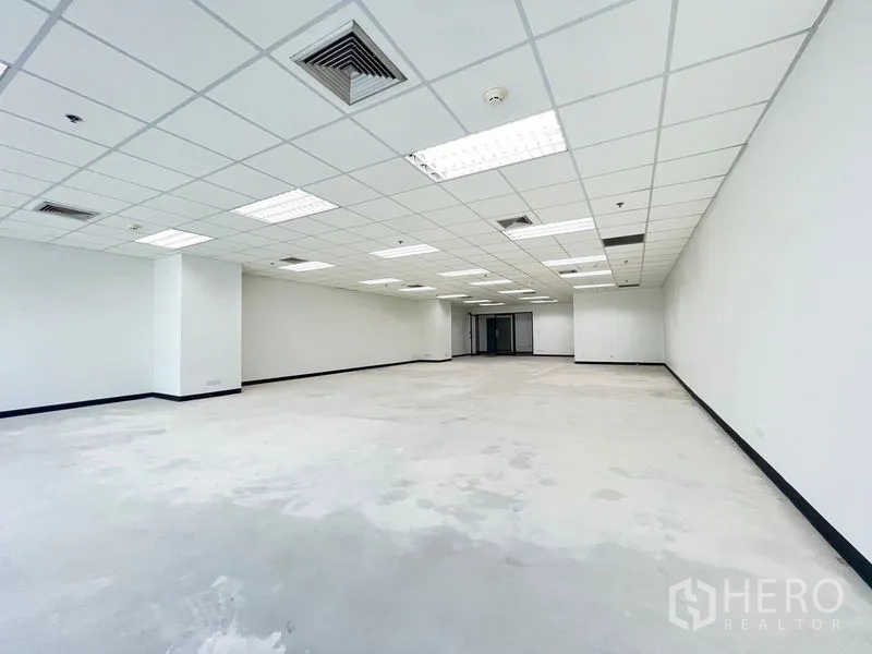Office Space for rent in Khlong Toei, Bangkok - Wide-angle view of a bright empty office showing tiled ceiling, recessed lights and central air-conditioning.