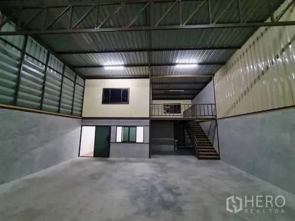 Warehouse for rent in Prawet, Bangkok - Open storage bay with metal walls, mezzanine level and staircase under bright lighting.