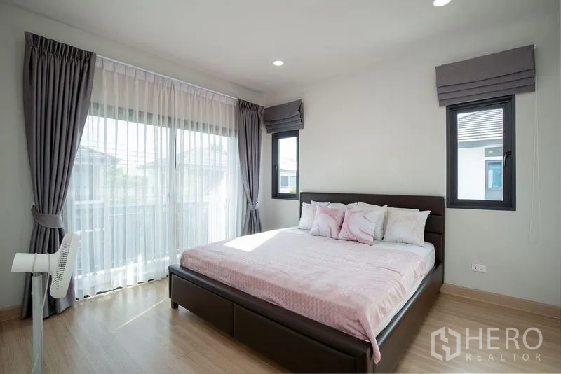 Detached House for rent in Bang Phli, Samut Prakan - Sunlit master bedroom with large windows, balcony access and gray drapes.
