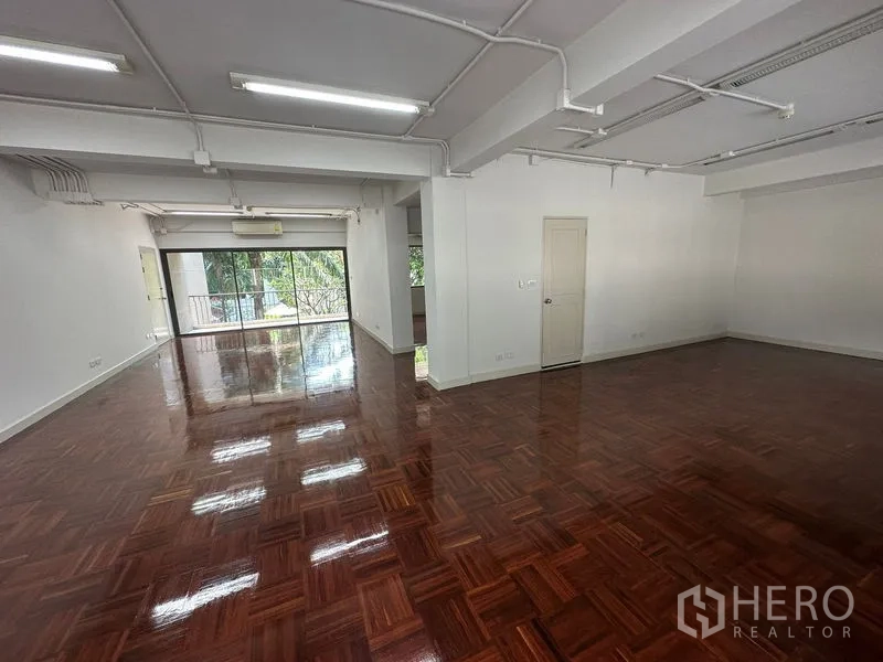 Office Space for rent - Large flexible office area with exposed ceiling lighting and shiny parquet floors.