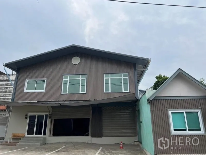 Warehouse for rent in Prawet, Bangkok - Two-storey warehouse exterior with roller shutter and on-site parking in Prawet, Bangkok.