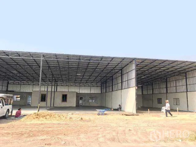 Warehouse for rent in Pathum Thani - Large steel-frame warehouse with a high roof and open concrete forecourt under construction.