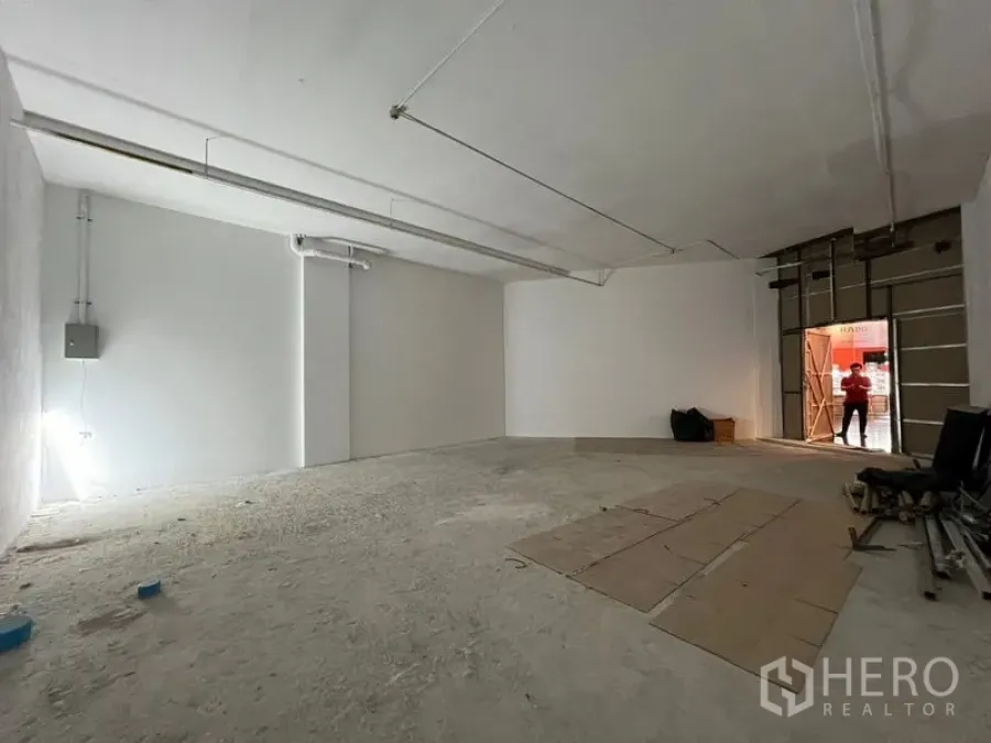 Retail Space for rent - Open-plan retail area with concrete floor, white interior and shutter-style entrance prepared for tenant fit-out.
