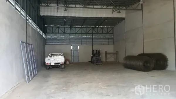 Warehouse for rent or sale in Sai Noi, Nonthaburi - Spacious warehouse interior with a high steel-truss ceiling, forklift area, and ample storage space.
