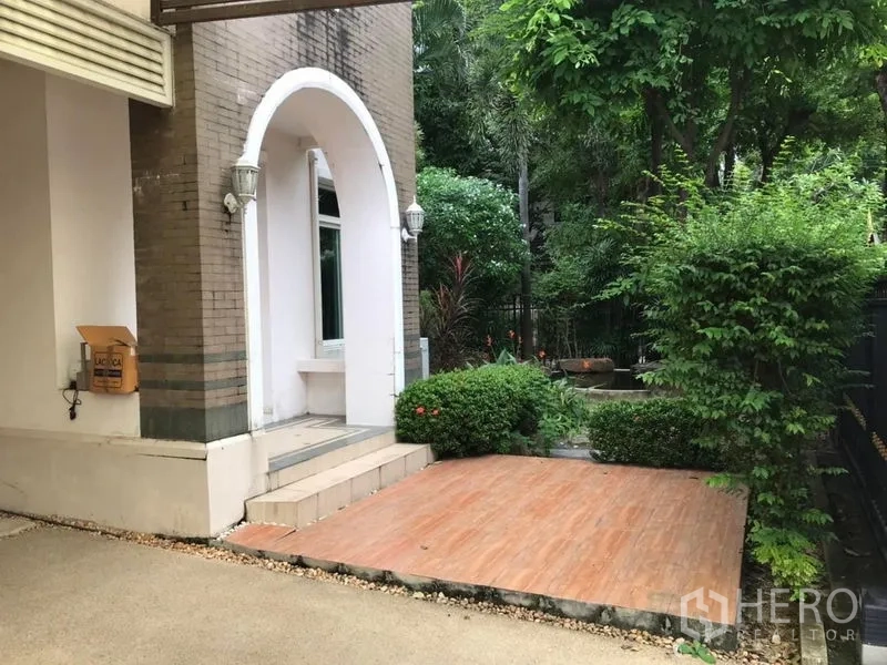 Detached House for rent in Bang Khen, Bangkok - Front entrance with arched doorway, terrace and landscaped shrubs.